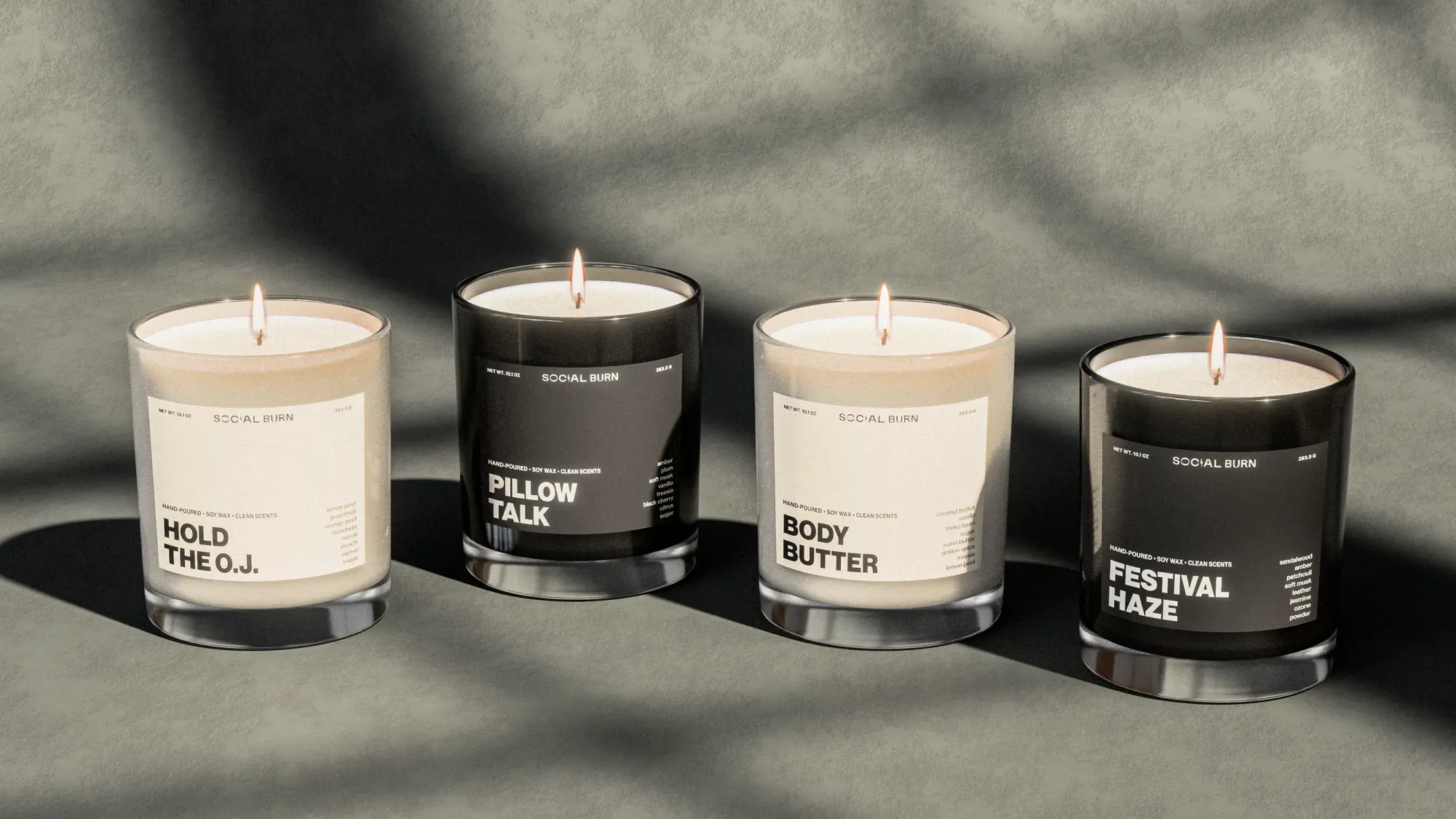 Four candles in glass on a textured surface with window shadows
